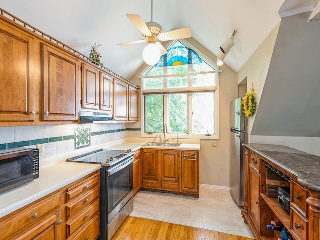 110 E 20th St N, Newton, IA 50208 - kitchen featuring appliances with stainless steel finishes, under cabinet range hood, brown cabinetry, vaulted ceiling, and ceiling fan