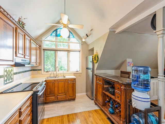 110 E 20th St N, Newton, IA 50208 - kitchen with stainless steel appliances, under cabinet range hood, a ceiling fan, brown cabinetry, and lofted ceiling