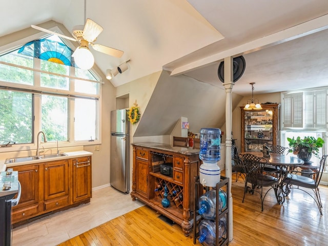 110 E 20th St N, Newton, IA 50208 - kitchen featuring a ceiling fan, lofted ceiling, brown cabinetry, light wood-style flooring, and freestanding refrigerator