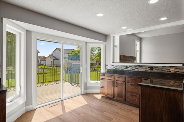 1217 NW Morningside Ct, Grimes, IA 50111 - kitchen with dark countertops, a textured ceiling, decorative backsplash, recessed lighting, and light wood-style floors