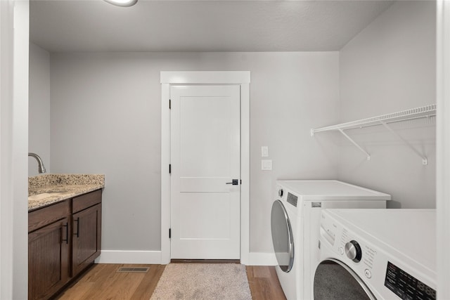 1217 NW Morningside Ct, Grimes, IA 50111 - laundry area featuring washer and clothes dryer, light wood finished floors, and cabinet space