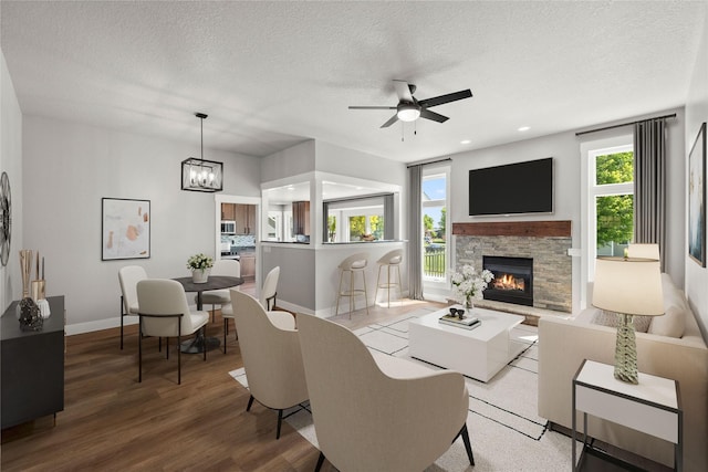 1217 NW Morningside Ct, Grimes, IA 50111 - living area featuring a ceiling fan, a textured ceiling, healthy amount of natural light, wood finished floors, and a fireplace