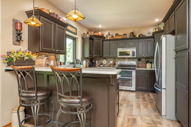 105 Everett Cir, Mingo, IA 50168 - kitchen with appliances with stainless steel finishes, a peninsula, decorative backsplash, light wood finished floors, and a kitchen breakfast bar