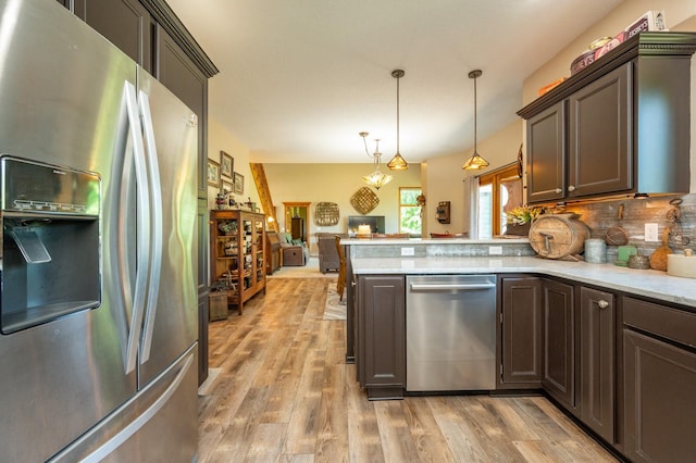 105 Everett Cir, Mingo, IA 50168 - kitchen with stainless steel appliances, a peninsula, light wood finished floors, pendant lighting, and decorative backsplash