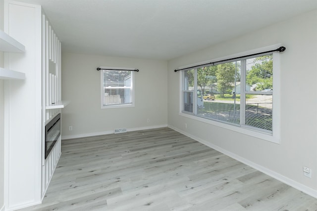 3113 E 36th Ct, Des Moines, IA 50317 - unfurnished dining area featuring light wood-type flooring and a glass covered fireplace