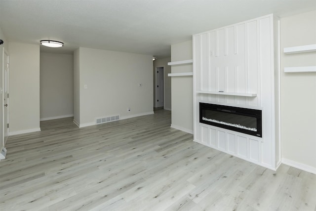 3113 E 36th Ct, Des Moines, IA 50317 - unfurnished living room with light wood-style floors and a fireplace