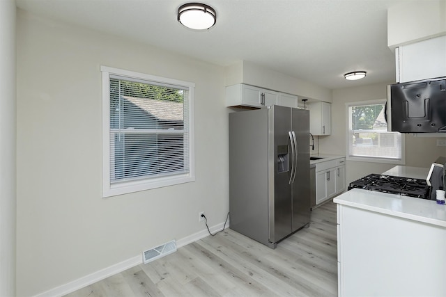 3113 E 36th Ct, Des Moines, IA 50317 - kitchen featuring stainless steel refrigerator with ice dispenser, gas stove, light wood-style floors, white cabinetry, and light countertops