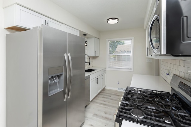 3113 E 36th Ct, Des Moines, IA 50317 - kitchen featuring appliances with stainless steel finishes, tasteful backsplash, light wood-style flooring, light countertops, and white cabinetry
