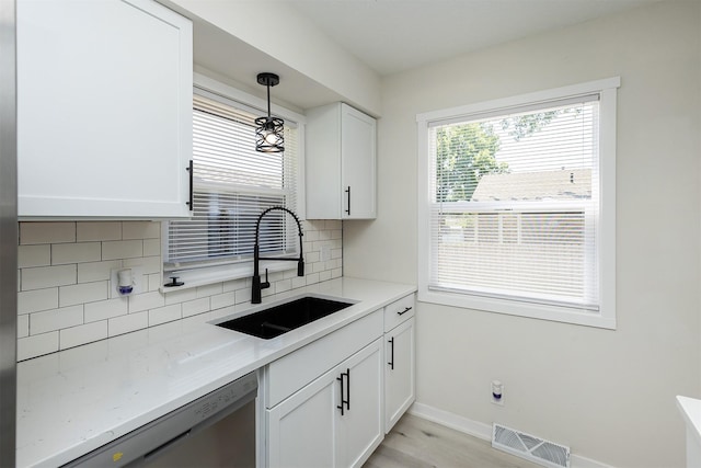 3113 E 36th Ct, Des Moines, IA 50317 - kitchen with dishwasher, decorative backsplash, white cabinets, decorative light fixtures, and light wood finished floors