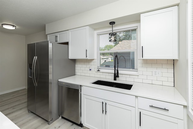 3113 E 36th Ct, Des Moines, IA 50317 - kitchen with stainless steel appliances, light wood finished floors, white cabinetry, light countertops, and backsplash