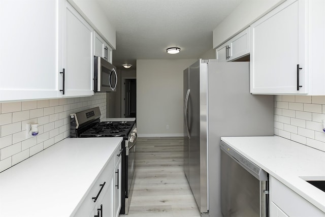 3113 E 36th Ct, Des Moines, IA 50317 - kitchen featuring appliances with stainless steel finishes, light wood finished floors, white cabinetry, and light countertops
