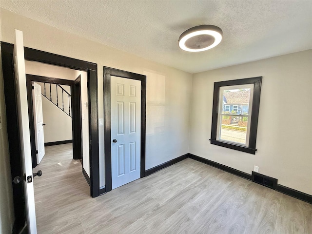 1254 E 16th St, Des Moines, IA 50316 - unfurnished bedroom with light wood-type flooring and a textured ceiling