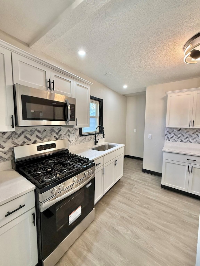 1254 E 16th St, Des Moines, IA 50316 - kitchen featuring stainless steel appliances, decorative backsplash, light countertops, white cabinets, and light wood finished floors