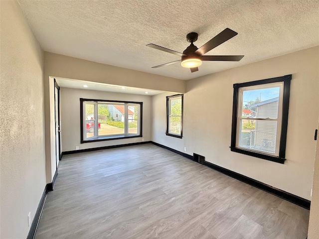 1254 E 16th St, Des Moines, IA 50316 - unfurnished room with wood finished floors, plenty of natural light, a ceiling fan, and a textured ceiling
