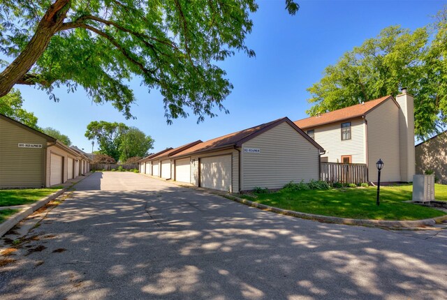 8628 Alpine Dr Unit C, Urbandale, IA 50322 - view of home's exterior with community garages, an outbuilding, a chimney, and a yard