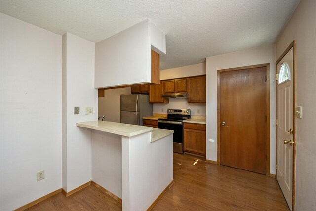 8628 Alpine Dr Unit C, Urbandale, IA 50322 - kitchen featuring stainless steel electric range, freestanding refrigerator, brown cabinets, a peninsula, and wood finished floors
