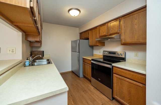 8628 Alpine Dr Unit C, Urbandale, IA 50322 - kitchen with stainless steel electric range, under cabinet range hood, freestanding refrigerator, light countertops, and light wood-style floors