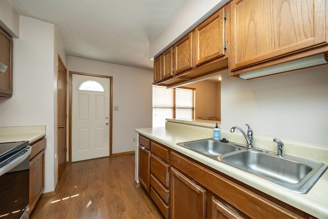 8628 Alpine Dr Unit C, Urbandale, IA 50322 - kitchen with stainless steel range with electric cooktop, light countertops, wood finished floors, brown cabinetry, and healthy amount of natural light