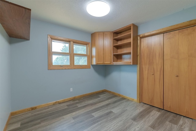 28453 530th Ave, Kelley, IA 50134 - unfurnished bedroom with light wood finished floors, a textured ceiling, and a closet