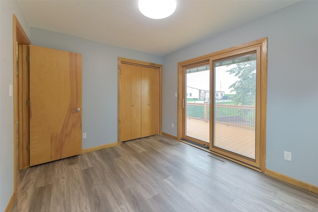 28453 530th Ave, Kelley, IA 50134 - unfurnished bedroom featuring wood finished floors, access to exterior, a closet, and a textured ceiling