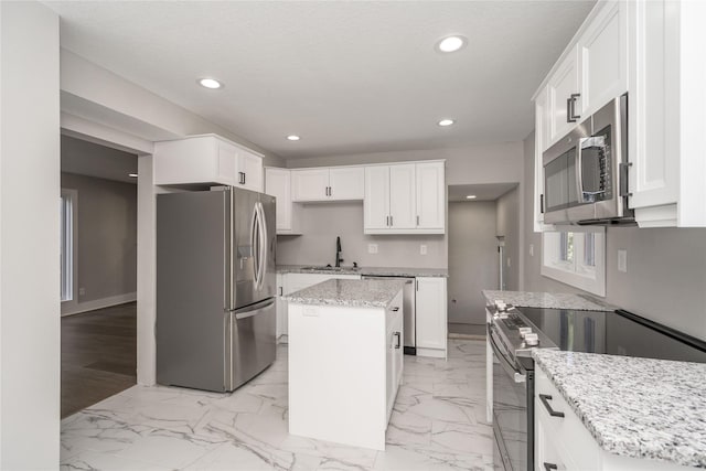 2715 Center St, Des Moines, IA 50312 - kitchen with stainless steel appliances, a center island, light marble finish flooring, recessed lighting, and white cabinetry