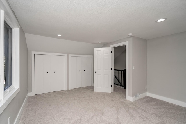 2715 Center St, Des Moines, IA 50312 - unfurnished bedroom featuring light carpet, two closets, recessed lighting, and a textured ceiling