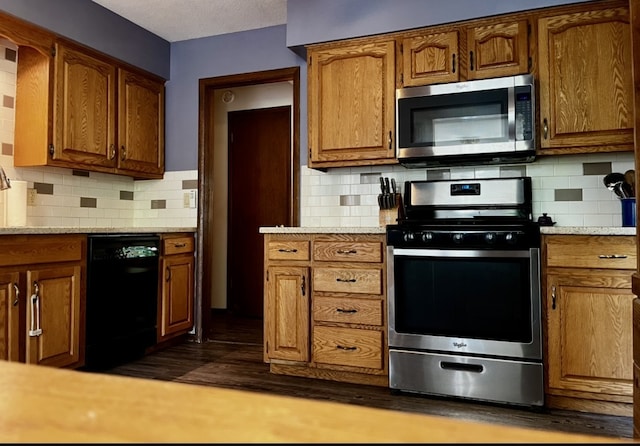 815 Knob Hill Dr, Des Moines, IA 50317 - kitchen with stainless steel appliances, light countertops, brown cabinetry, decorative backsplash, and a textured ceiling