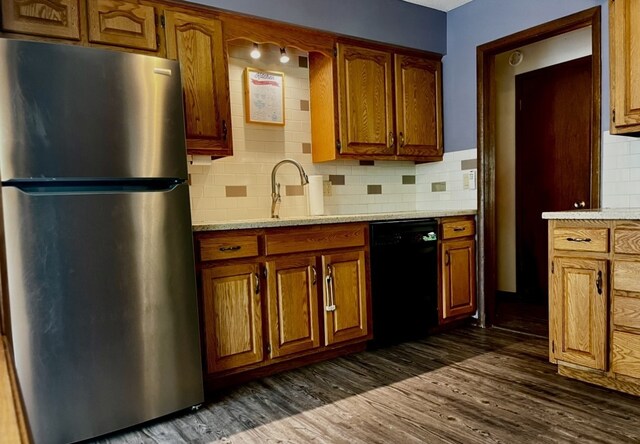 815 Knob Hill Dr, Des Moines, IA 50317 - kitchen with freestanding refrigerator, dishwasher, decorative backsplash, dark wood-style floors, and brown cabinets