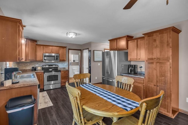 1329 Joshua Cir SE, Bondurant, IA 50035 - kitchen featuring stainless steel appliances, dark wood-type flooring, tasteful backsplash, a ceiling fan, and brown cabinets
