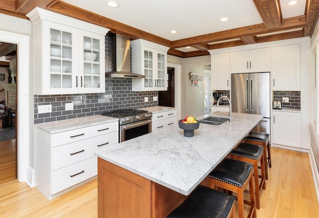 642 Polk Blvd, Des Moines, IA 50312 - kitchen with wall chimney exhaust hood, premium appliances, light wood-style floors, decorative backsplash, and a breakfast bar