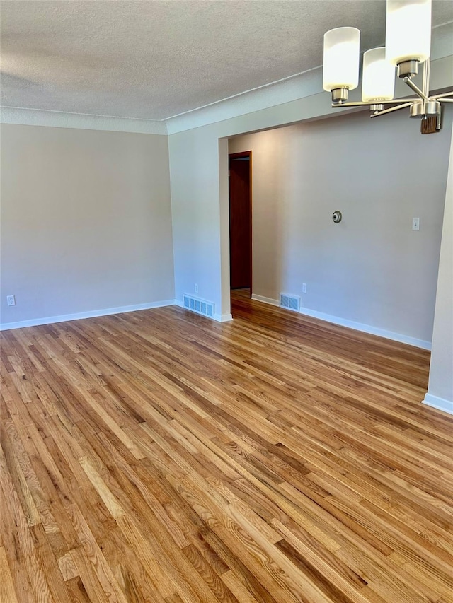 2327 Glenbrook Dr, Des Moines, IA 50316 - empty room with light wood-style floors, a chandelier, and a textured ceiling