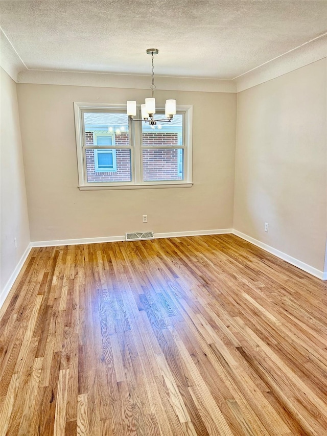 2327 Glenbrook Dr, Des Moines, IA 50316 - spare room featuring light wood-style floors, a textured ceiling, and a chandelier