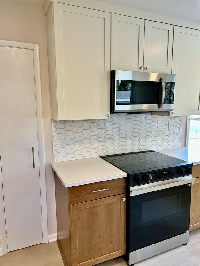 2327 Glenbrook Dr, Des Moines, IA 50316 - kitchen with stainless steel microwave, black / electric stove, light countertops, and backsplash