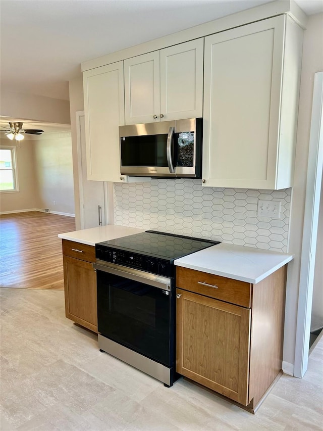 2327 Glenbrook Dr, Des Moines, IA 50316 - kitchen with range with electric cooktop, stainless steel microwave, a ceiling fan, tasteful backsplash, and light countertops
