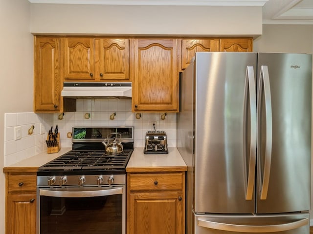 2906 Watrous Ave, Des Moines, IA 50321 - kitchen with stainless steel appliances, under cabinet range hood, light countertops, tasteful backsplash, and brown cabinetry