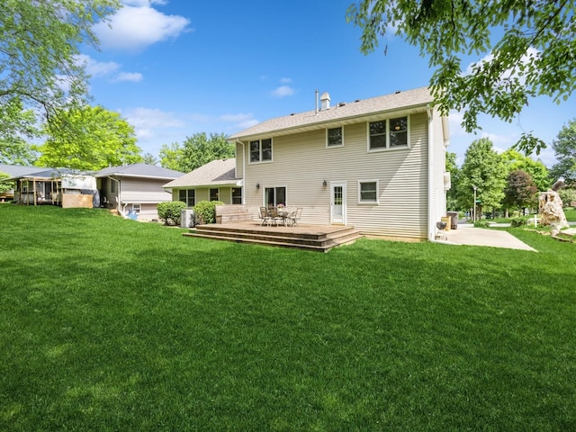 2906 Watrous Ave, Des Moines, IA 50321 - back of house featuring a deck, a lawn, and a patio