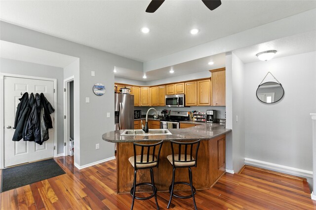 711 Kitterman Cir, Norwalk, IA 50211 - kitchen with stainless steel appliances, dark wood-type flooring, a peninsula, ceiling fan, and a kitchen breakfast bar