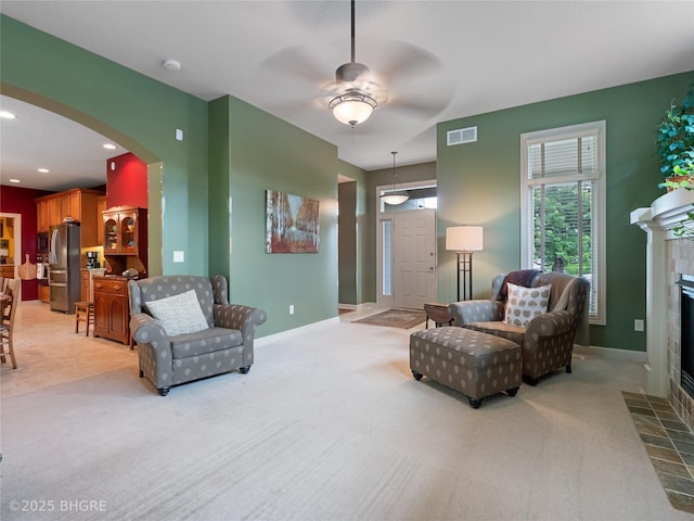 4710 76th St, Urbandale, IA 50322 - living room with light carpet, a ceiling fan, a fireplace, arched walkways, and recessed lighting
