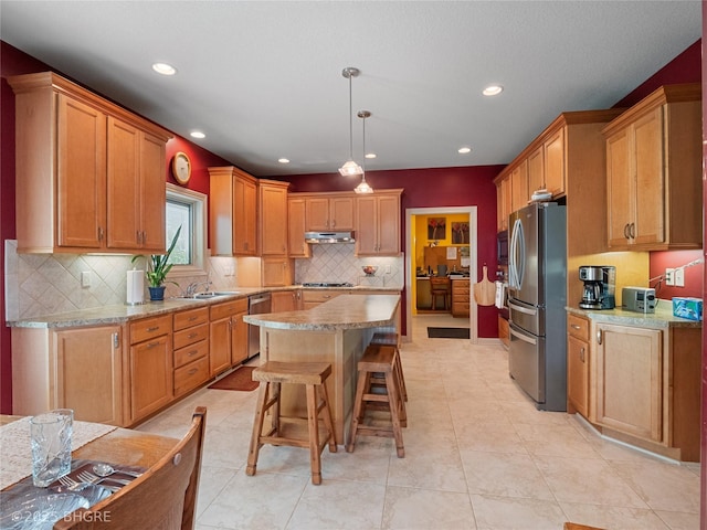 4710 76th St, Urbandale, IA 50322 - kitchen with stainless steel appliances, a kitchen island, tasteful backsplash, a kitchen breakfast bar, and under cabinet range hood