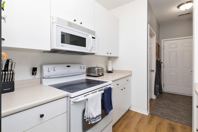 2323 E Porter Ave Unit 36, Des Moines, IA 50320 - kitchen with white appliances, light wood-type flooring, light countertops, and white cabinets
