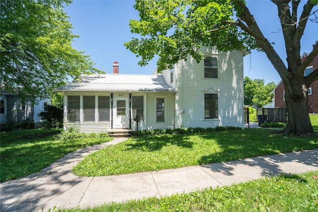 600 S 3rd Ave W, Newton, IA 50208 - view of front facade with a chimney, a front lawn, a metal roof, a sunroom, and a standing seam roof