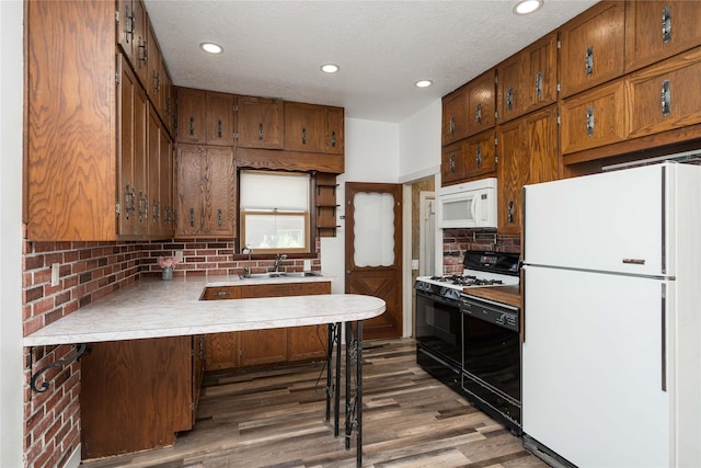 600 S 3rd Ave W, Newton, IA 50208 - kitchen featuring black appliances, a peninsula, wood finished floors, light countertops, and decorative backsplash