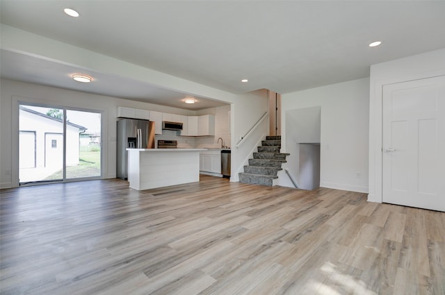 4132 E 24th Ct, Des Moines, IA 50317 - unfurnished living room featuring light wood finished floors, recessed lighting, and stairs