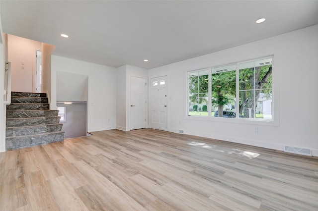 4132 E 24th Ct, Des Moines, IA 50317 - unfurnished living room featuring light wood finished floors, stairs, and recessed lighting