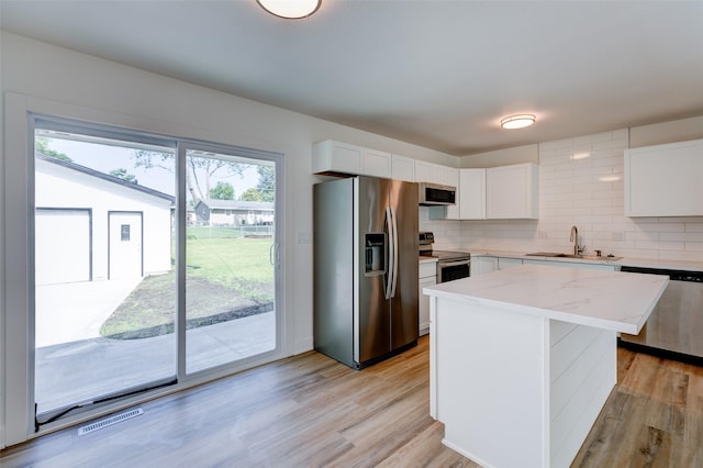 4132 E 24th Ct, Des Moines, IA 50317 - kitchen featuring appliances with stainless steel finishes, white cabinets, tasteful backsplash, and a kitchen island