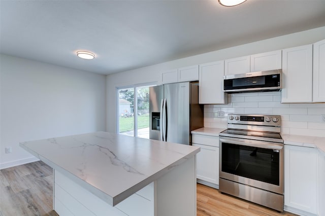 4132 E 24th Ct, Des Moines, IA 50317 - kitchen with appliances with stainless steel finishes, light wood finished floors, backsplash, and white cabinetry