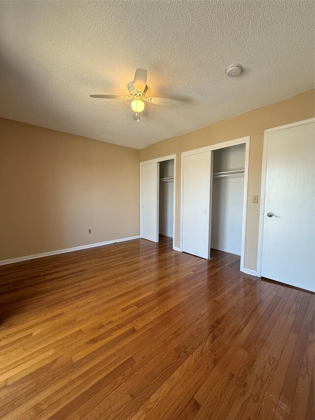 2519 W 1st St, Ankeny, IA 50023 - unfurnished bedroom with two closets, wood finished floors, a textured ceiling, and ceiling fan