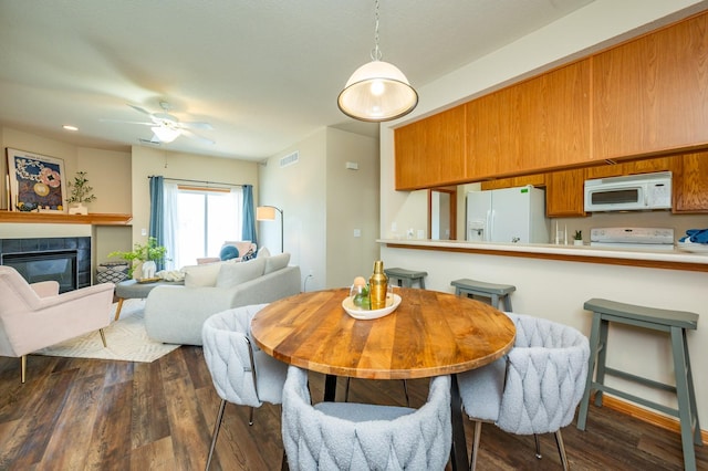 8601 Westown Pkwy Unit 18211, West Des Moines, IA 50266 - dining room with dark wood-style floors, a tiled fireplace, and ceiling fan
