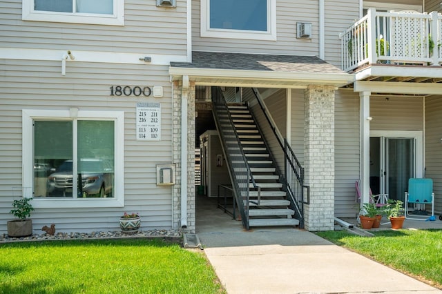8601 Westown Pkwy Unit 18211, West Des Moines, IA 50266 - doorway to property featuring a balcony, a shingled roof, and a lawn