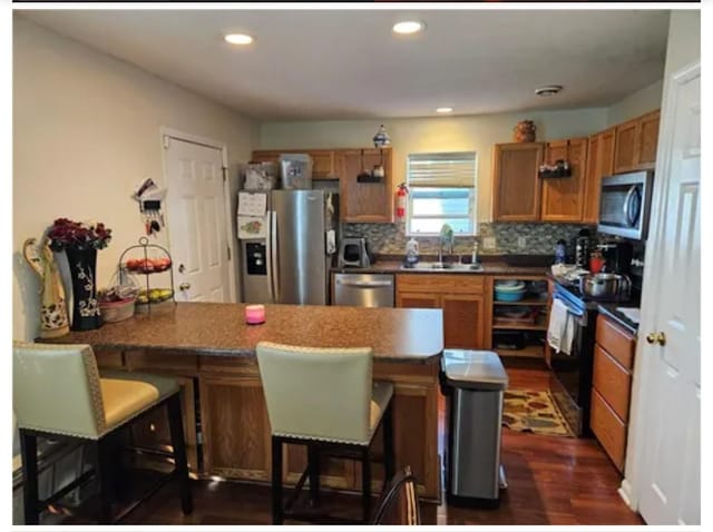 1096 Buchanan St, Des Moines, IA 50316 - kitchen with appliances with stainless steel finishes, a peninsula, dark countertops, dark wood-type flooring, and a kitchen breakfast bar